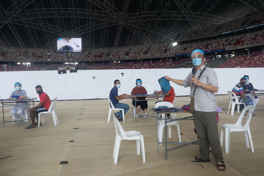 Local artist, Jimmy Ong (standing) explaining the meaning of the “Stay Home Quilt” art project to the migrant workers. (Photo by Bernard Ng Jia Han)