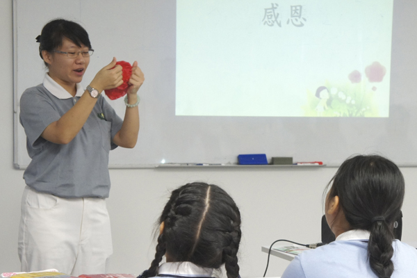 Volunteer Audrey Koh explaining to the class how to make the craft flowers (Photo by Chen Run Jiao)