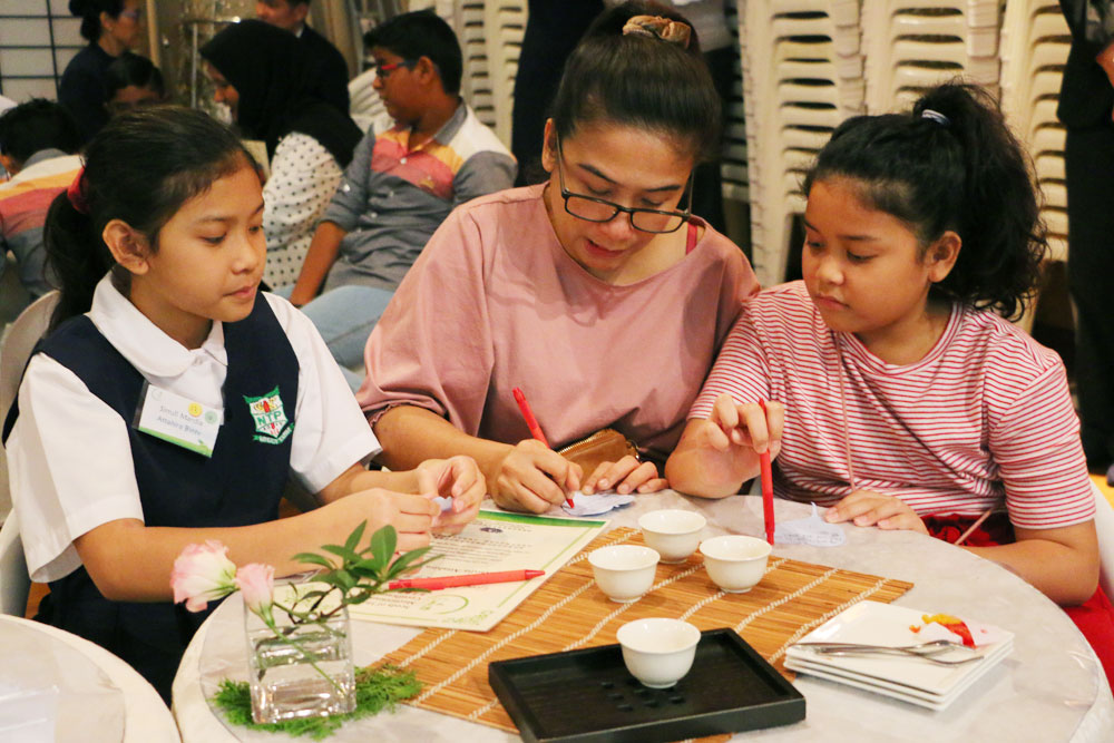 Parents and their children penning down words of gratitude and well-wishes for each other on a card (Photo by Ng Sher Lin)