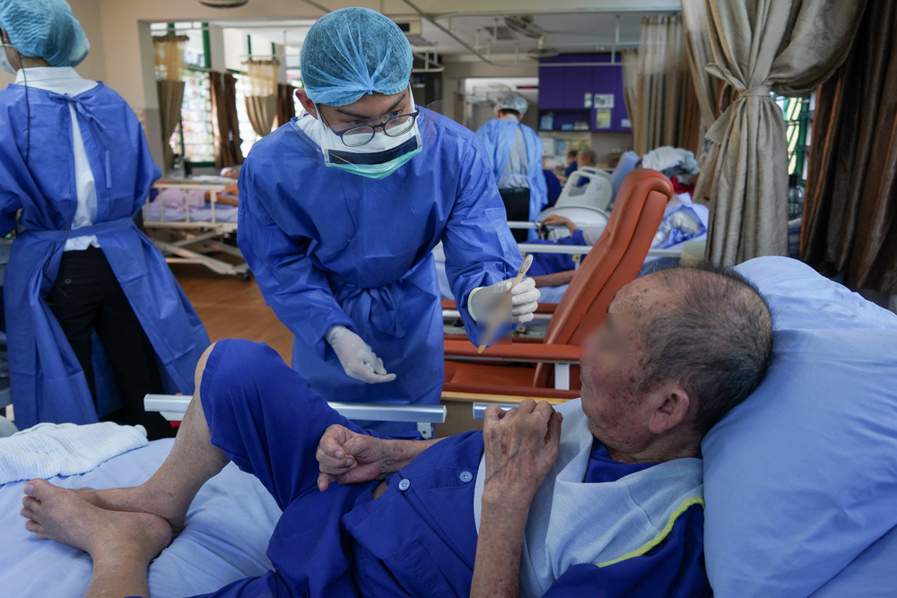 Prospective dental student Mr Marcus Low giving a patient at LAMH (Silat) a new toothbrush with his name written on it. (Photo by Chan May Ching)